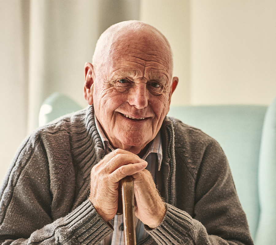 Älterer Mann sitzt und sieht glücklich aus